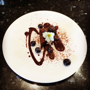 Delicious brownie with chocolate sauce, blueberries and edible pansies